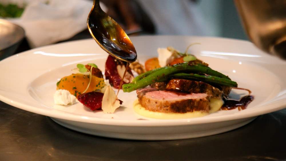 A gourmet meal being dressed with jus