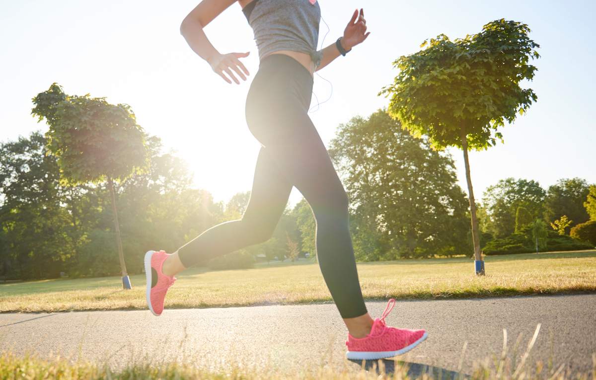 A woman on a run in a park wearing pink trainers