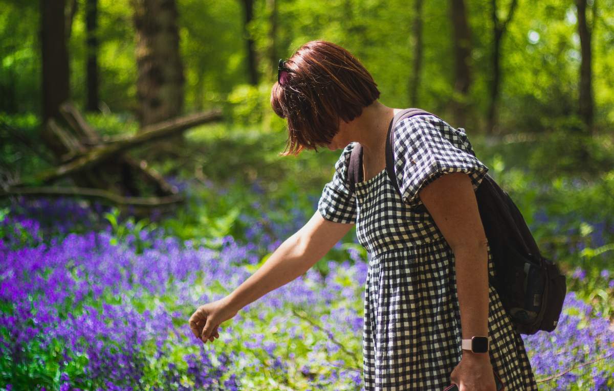 Woman touching bluebells in a woodland setting